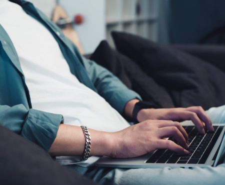 CMS Mann sitzt auf Couch mit Laptop